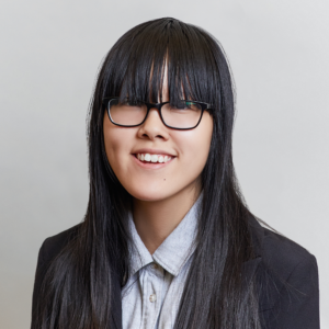 Asian woman with long black hair and long bangs with a black blazer and buttoned up collared shirt